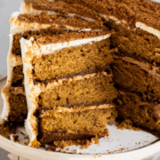 Slice of pumpkin biscoff cake showing biscoff cookie crust and pumpkin spice cake layers