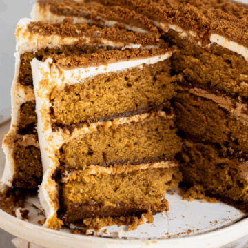 Slice of pumpkin biscoff cake showing biscoff cookie crust and pumpkin spice cake layers