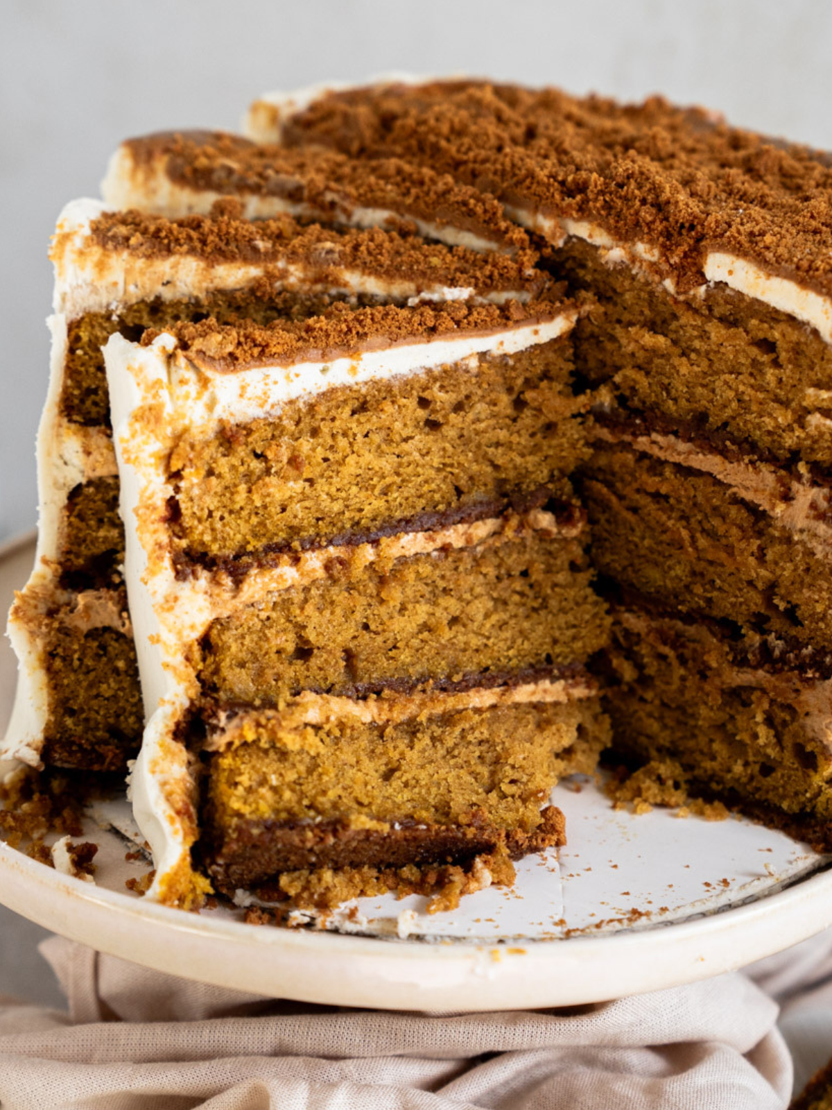 Slice of pumpkin biscoff cake showing biscoff cookie crust and pumpkin spice cake layers
